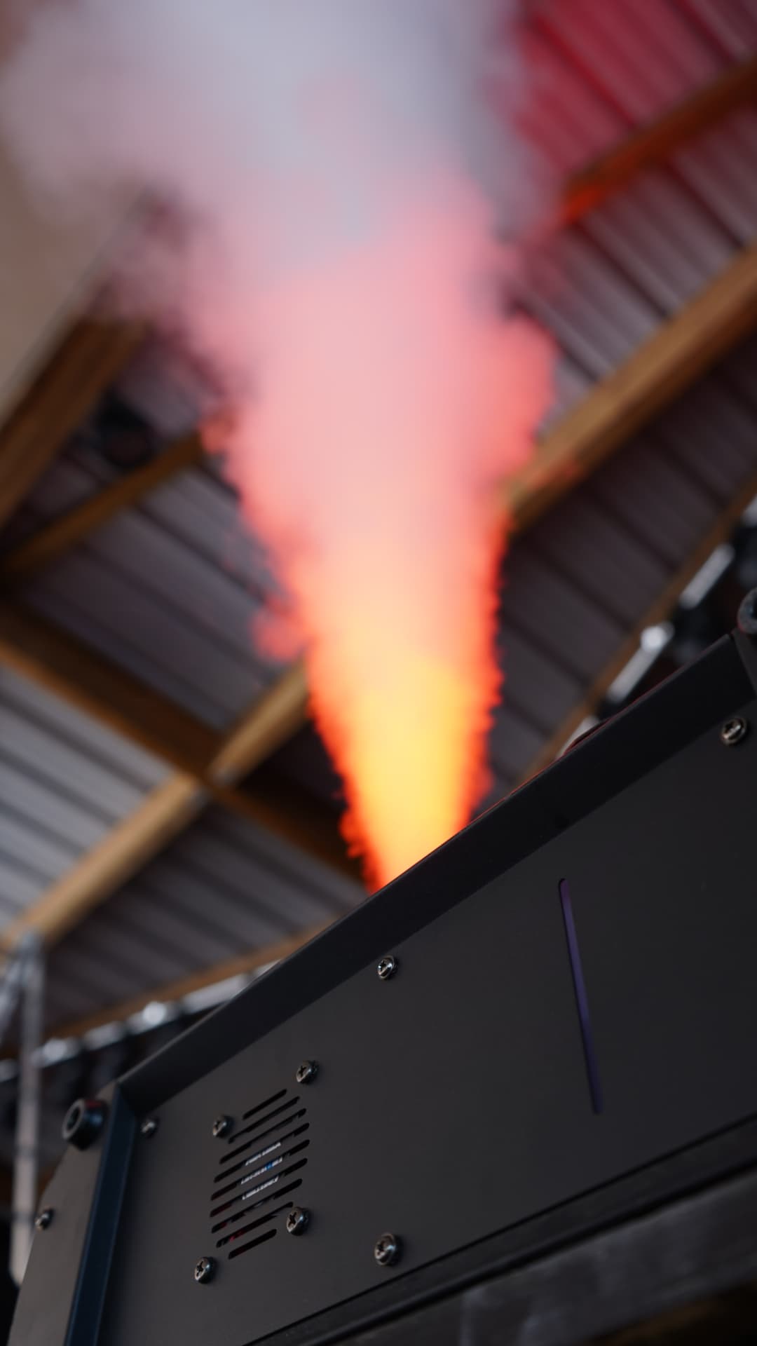 Machine à fumée en action, jet éclairé en orange sous un pont lumière en Gironde