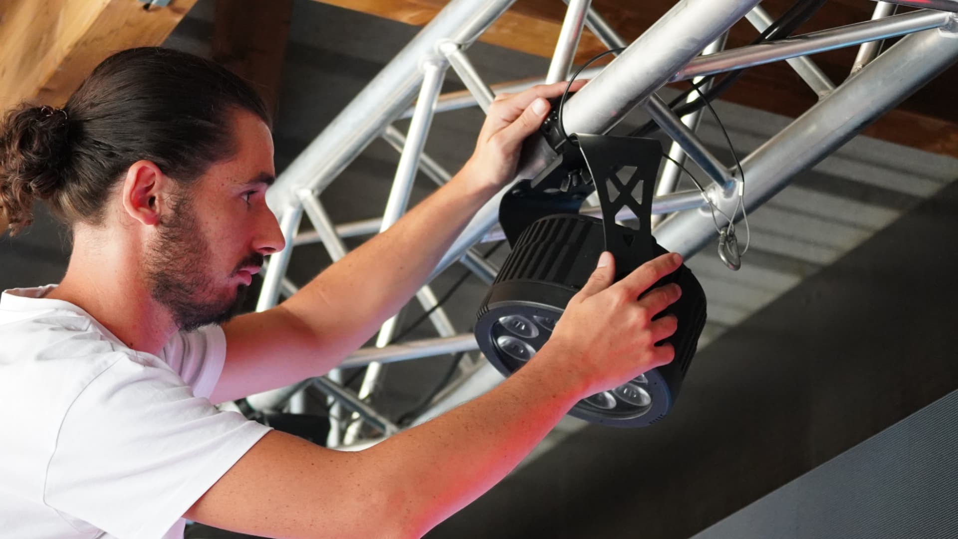Technicien Peach Technique accrochant une lyre motorisée sur un pont en structure alu